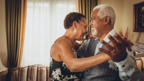 Older couple dancing in living room.