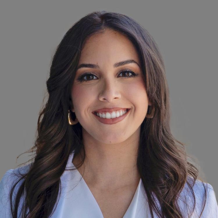 Female doctor with brown hair and brown eyes smiling for the camera.