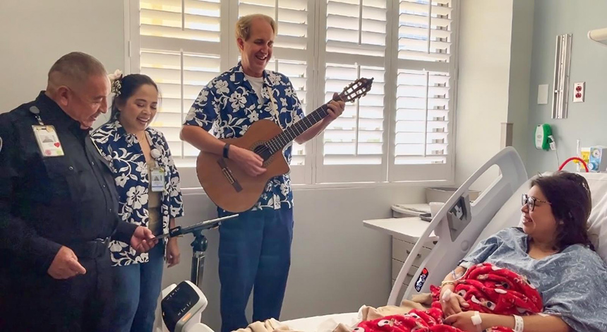 “Healing Harmonies” nurse performers, Rosie Obligacion and Chris Wright, with the help of hospital security guard, Jesus Bega, bring light to a patient’s stay singing ‘Here Comes the Sun.’