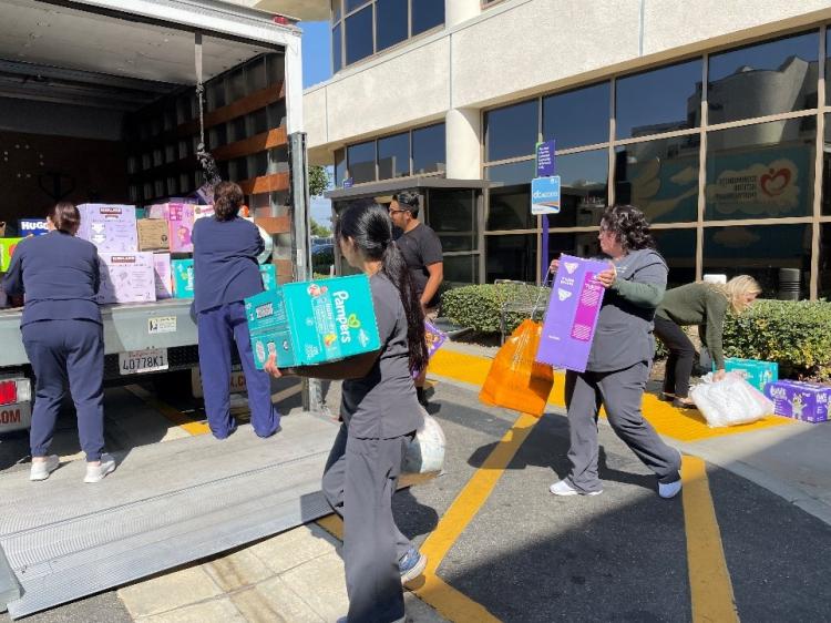 Nurses taking diaper boxes into a large loading truck.