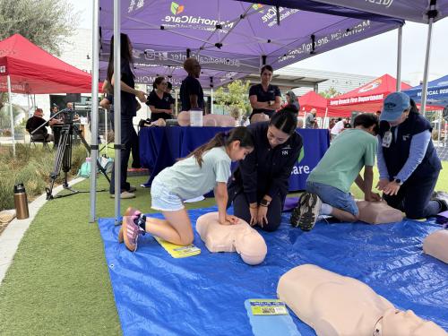 Two young siblings learn hands-only CPR from MemorialCare Long Beach Medical Center nurses during a “Sidewalk CPR” training event with the Long Beach Fire Department, highlighting the importance of building lifesaving skills at any age.