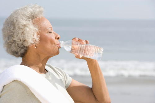 Senior woman drinking water at the beach.