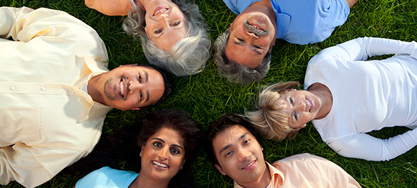 Image of six people lying on grass and looking up