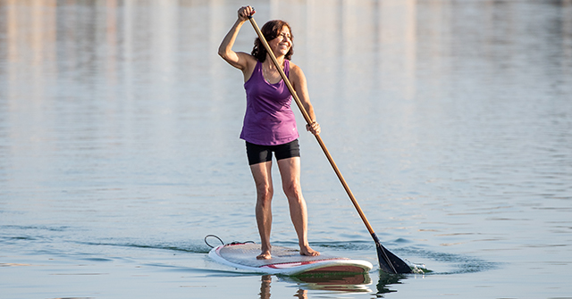 Image of joint replacement patient, Monica, paddle boarding