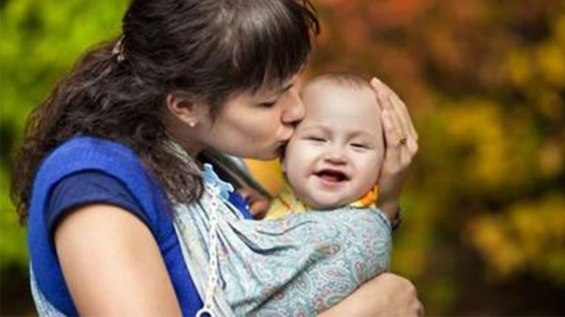 Image of a mom with a happy baby in a sling 
