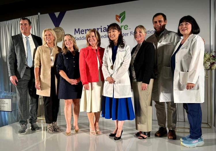 Members of the MemorialCare Saddleback Medical Center Foundation Standing in front of a sign with their logo to take a photo with Dr. Linda Chan. 