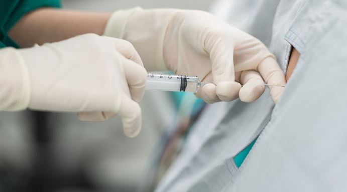 Close up image of surgeon hands inserting a needle into a back