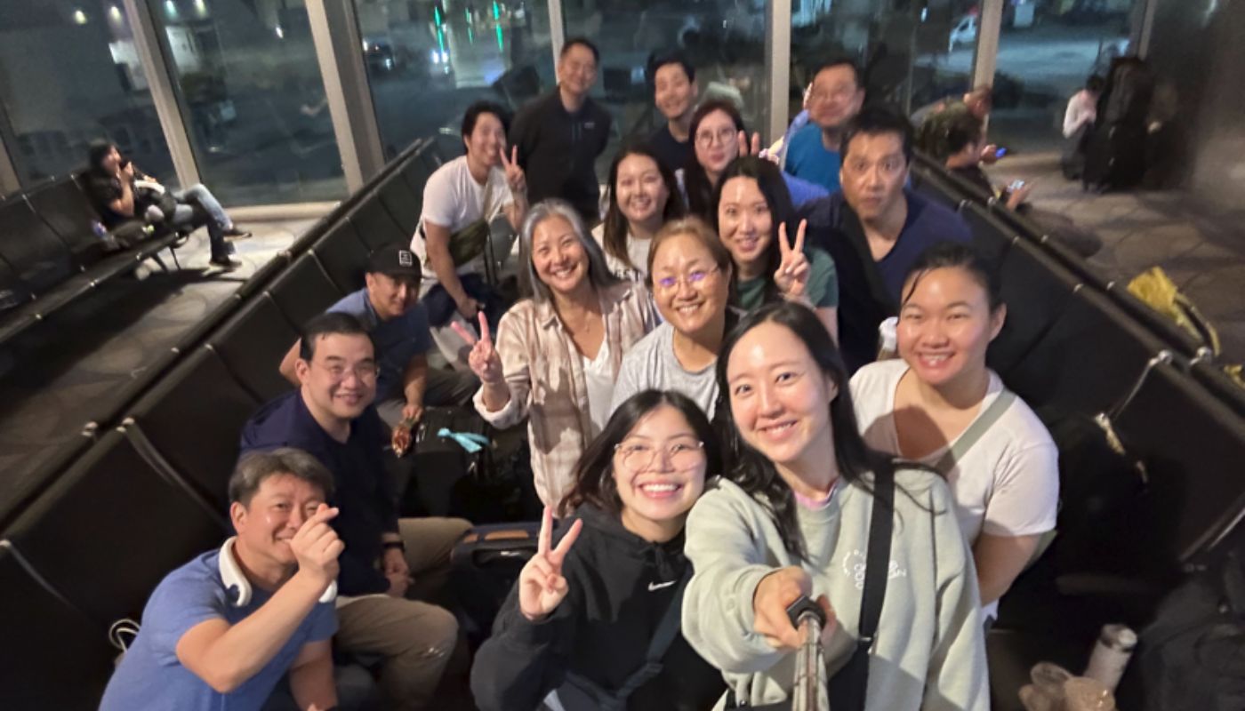A group of volunteers stand in between the seats of an airport gate.